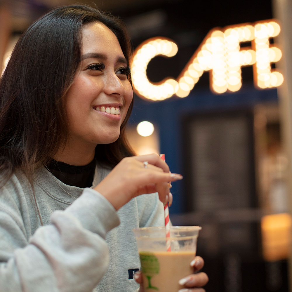 Female student drinking coffee at the container cafe (square)