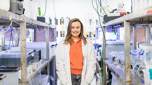 Female postgraduate student in a lab coat smiling in a laboratory