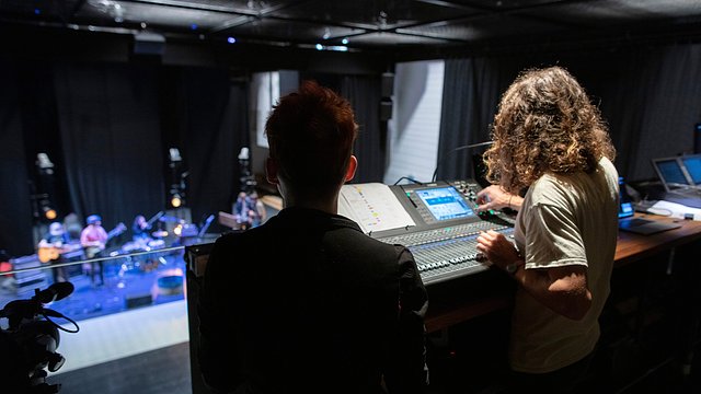 Music, audio and sound production students using sound equipment in The House to set up a band performance 