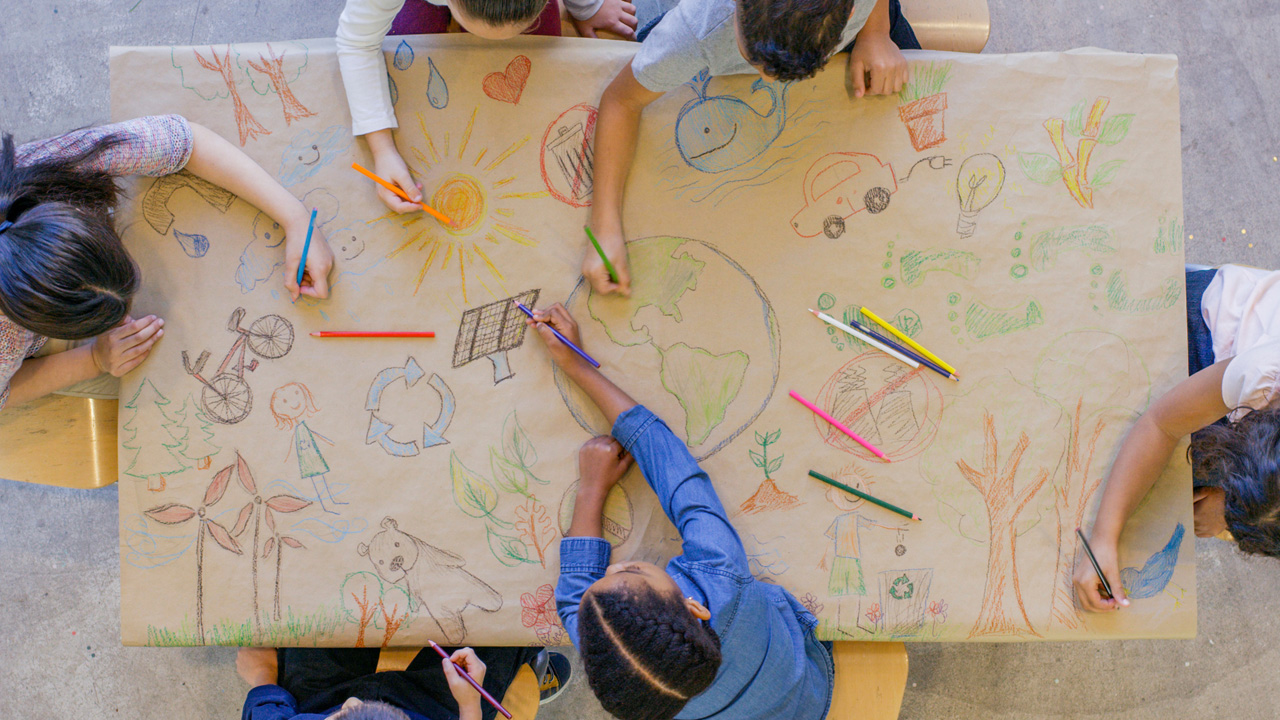 Aerial shot of children drawing on large sheet of paper